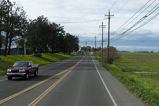 istock Road scene with vehicles and fields on a cloudy day in a rural area 2254556499