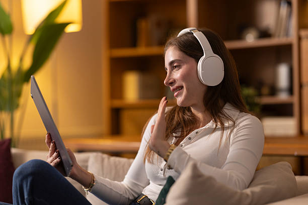 istock Young woman video calling using digital tablet and headphones at home 2254556640