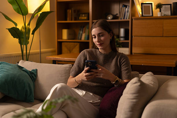 istock Young woman relaxing on sofa browsing smartphone 2254556962