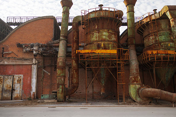 The image is of a building with a spiral staircase and many windows. Scene is eerie and unsettling, as the building appears to be abandoned and in disrepair