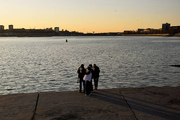 People standing on a waterfront by a river at sunset in Irkutsk, Russia, April 28, 2021.