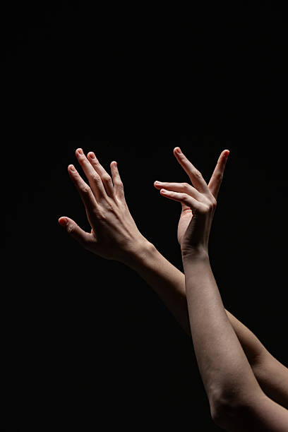 istock Two expressive female hands with red nails reach upward in a delicate, artistic gesture against a black background, emphasizing contrast and form 2254569244