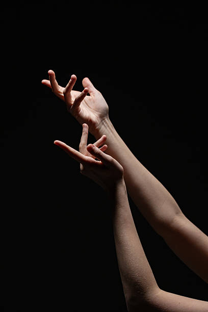 istock Two feminine hands caught in a dynamic, graceful motion with soft lighting against a black background. Evokes emotion and elegance in a minimalist style 2254569256