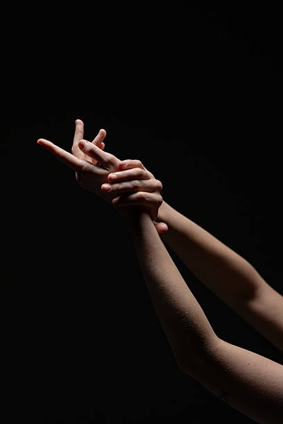istock Female hands in a poised, expressive gesture illuminated against a black background. Graceful and emotive composition with minimal lighting 2254569259