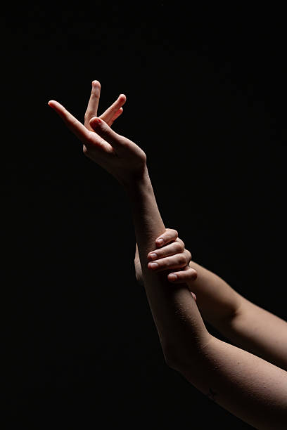 istock Female hands in a poised, expressive gesture illuminated against a black background. Graceful and emotive composition with minimal lighting 2254569260