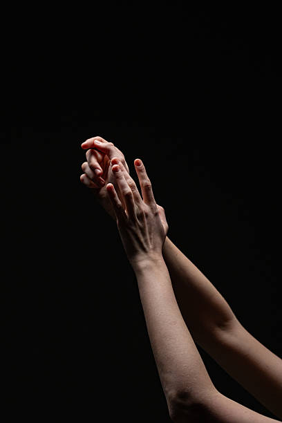 istock Two feminine hands with red nails gracefully posed against a dark background, emphasizing skin texture and form. Suitable for beauty or dramatic artistic concepts 2254569277