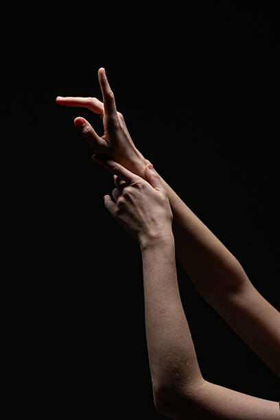 istock Female hands in an elegant, expressive gesture with soft lighting against a black background. Emphasizes form, texture, and emotion 2254570533
