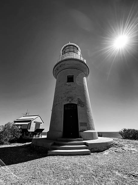 A solitary lighthouse tower stands tall against a bright sun-drenched sky, showcasing resilience and guidance.