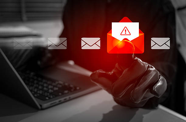 istock Anonymity hacker or scammer wearing black gloves opens red envelope alert email on laptop. Phishing, malware, or virus attacks. Concept of cybercrime, data breach, and online email security threats. 2254575274