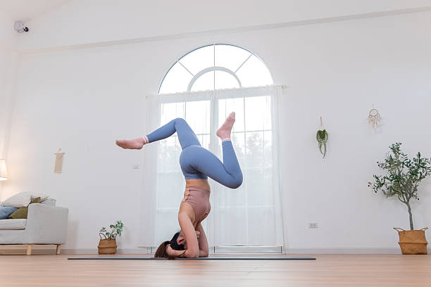 istock Athletic Woman Practicing an Advanced Headstand Yoga Pose for a Home Workout in a Bright Living Room. 2254576660