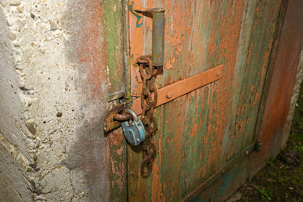 Silver padlock and latch on an old metal door