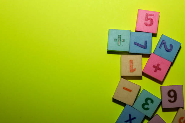 istock A vibrant educational composition of multicolored toy blocks featuring numbers and mathematical signs (plus, minus, division, multiplication), set against a rich lemon-yellow background. 2254578811