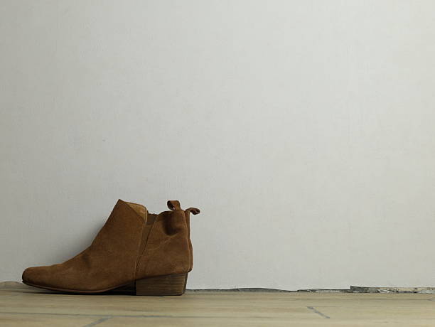istock Pair of suede boots standing on the floor against a white wall background. 2254580320