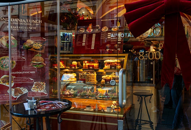 Krakow, Poland – December 13, 2025: A cafe window showcases cakes and desserts illuminated by warm interior lighting, inviting passersby during the winter Christmas market season in the Old Town.