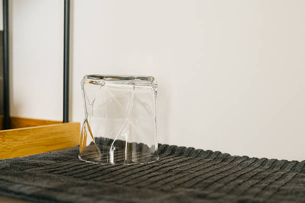 Empty glass upside down on black ribbed mat in minimalist setting.