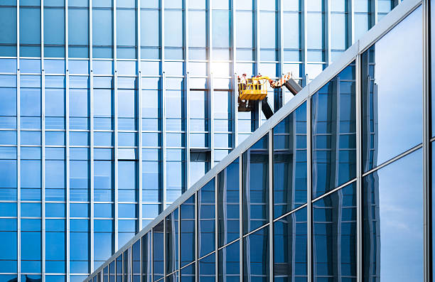 Maintenance works being done on a modern office building, work on a facade from a hydraulic boom lift
