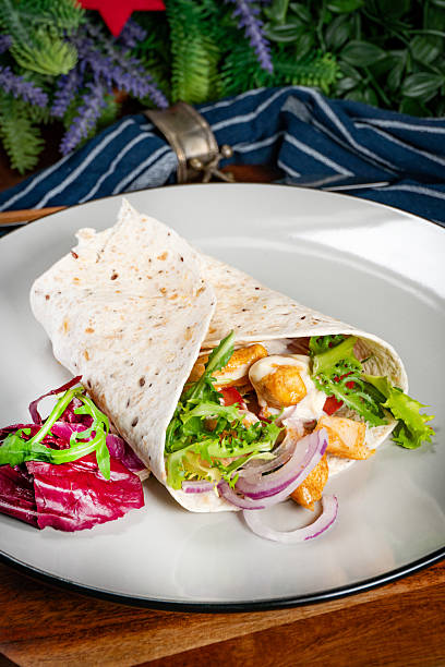 istock Wholegrain tortilla wraps with vegetables and chicken on a plate. 2254585710