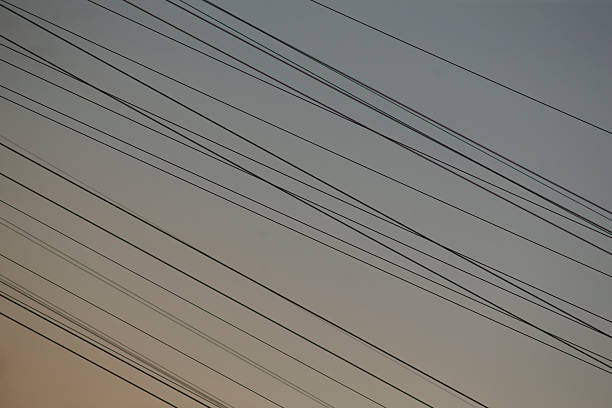 Close abstract view of diagonal powerline pattern against soft sky, repetitive cables creating graphic rhythm, minimalist and modern composition suited for background, texture,