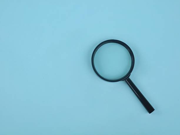 istock Black magnifying glass isolated on a light blue background 2254589948