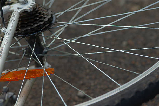 Detailed view of bicycle component, Closeup shot highlighting bike spokes and reflector, An upclose image showcasing bicycle wheel details and roadway surface in daytime