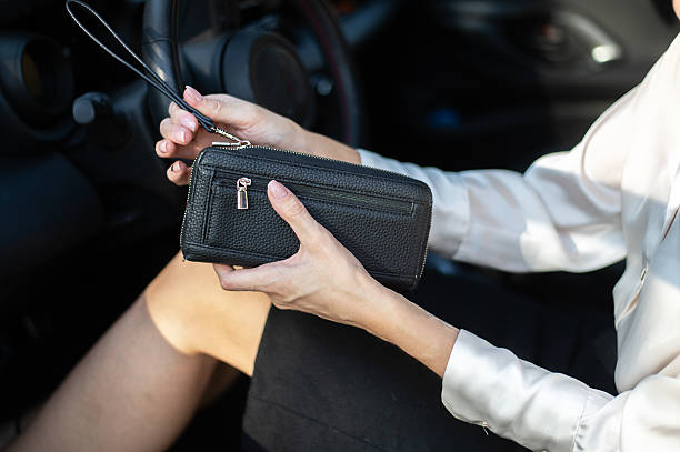 istock Woman holding black leather wallet while sitting in car 2254593778