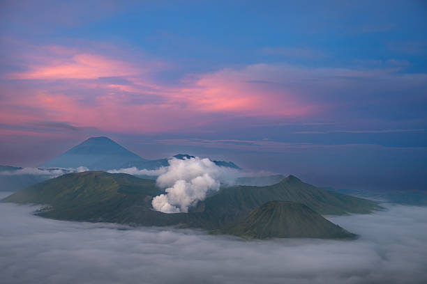 Mount Bromo at dawn amidst mist and smoke with pink sky, East Java, Indonesia