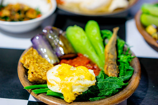 Indonesian spicy (sambal) on an earthenware plate with fried eggplant, fried tempeh, fried salted fish and chayote.