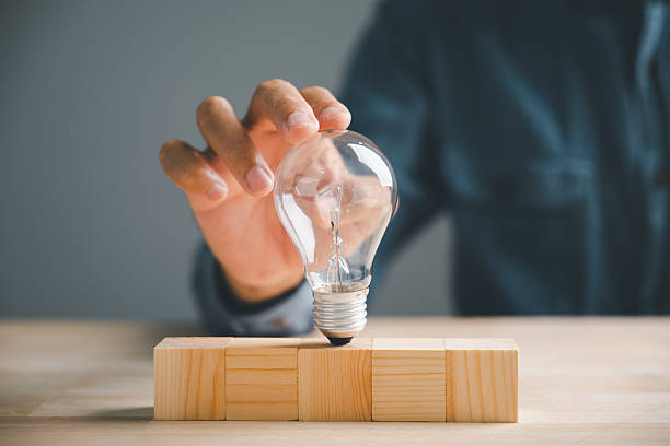istock A hand holding a light bulb over three wooden blocks. Concept for ideas and innovation. 2254596100