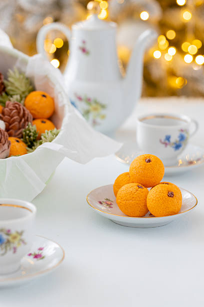 Zephyr arrangement featuring pine cones, cotton bolls, and oranges nestled in white tissue paper, creating a festive atmosphere with natural elements and seasonal charm