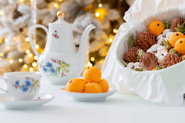 istock Zephyr Vibrant orange sweets arranged on a delicate plate beside a festive bowl filled with pinecones and greenery, creating a warm and inviting holiday atmosphere 2254596296