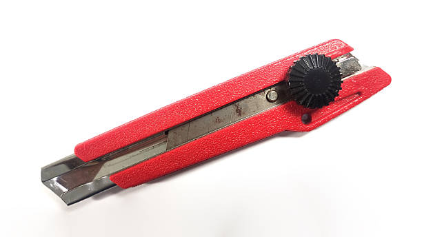 Close-up of a red utility knife with metal blade isolated on white background. Used for cutting paper, cardboard, packaging, and DIY or construction work. Sharp hand tool concept.