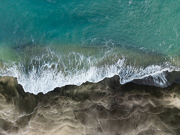 istock Waves crashing on sandy beach at a coastline during daylight with clear blue ocean water and patterns in the sand 2254596963