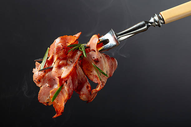 istock Hot fried bacon slices with rosemary on a fork. 2254597657