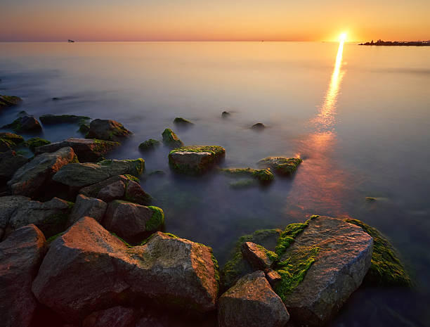 Seascape at sunset. Sea on a long shutter with stones and rocks.