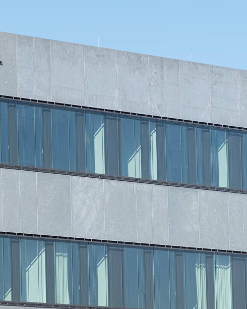 istock Modern office building with large glass windows reflecting the clear sky against a minimalistic architectural design 2254598350