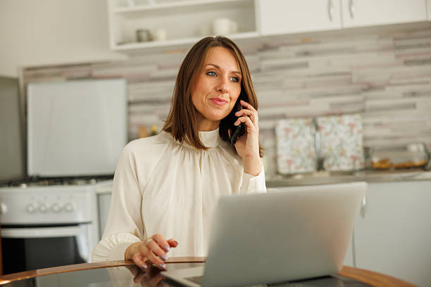istock Business woman having phone conversation and working using laptop computer at home 2254601763