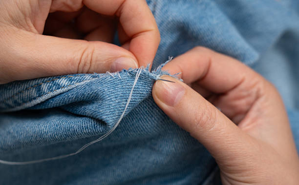 istock Woman mends jeans by hand with needle 2254608367