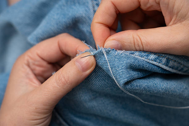 istock Woman mends jeans by hand with needle 2254608685