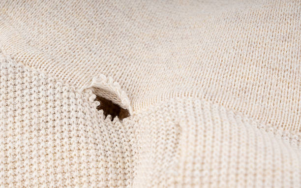 istock Torn fabric with a hole close-up. Damaged textiles background, old rip cotton material 2254608753