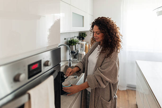 istock Woman in Cozy Robe Making Coffee at a Modern White Kitchen in Morning Light Today 2254609543