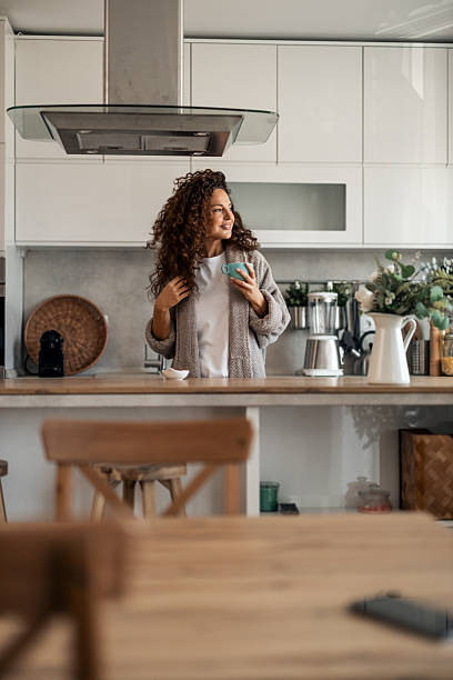 istock Woman Smiles With Coffee Mug In Modern Cozy Kitchen During Morning Routine 2254609620