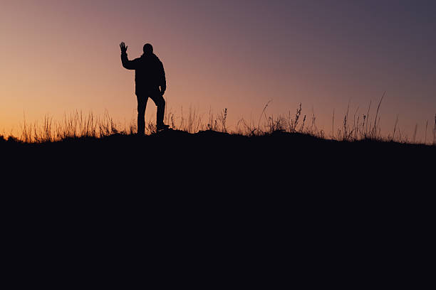 Silhouette of a man standing on a hill. Sunset hours. It's cloudy. Location Nevşehir, Cappadocia. A mysterious man standing.