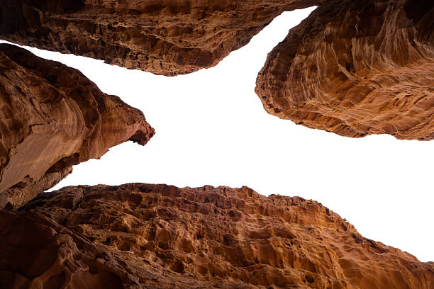 A dramatic view from inside a sandstone canyon, looking up at the open sky. Rugged red walls and textured rock formations create a natural architectural frame for travel or geology themes.