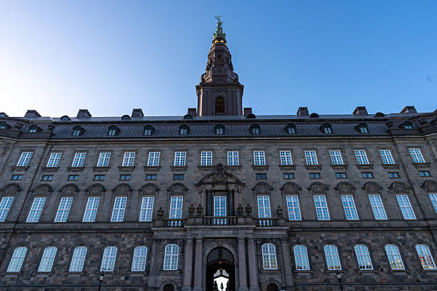 The grand façade of Christiansborg Palace in Copenhagen rises beneath a clear blue winter sky, showcasing centuries of Danish political and architectural history.