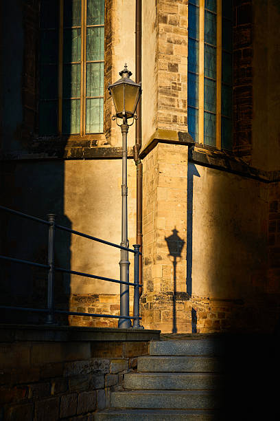 Lantern with shadow in front of the facade of St. John's Church, Johanniskirche in Magdeburg, Germany at sunset