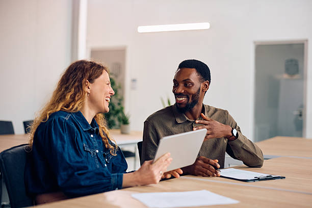 istock Happy colleagues talking while working on digital tablet in the office. 2254628505