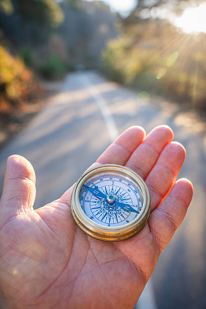 istock Hand holding an antique compass pointing forward on a road, symbolizing guidance and future direction 2254628874