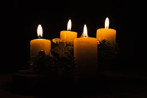 Four candles burning on an Advent wreath against a dark background. Christmas tradition