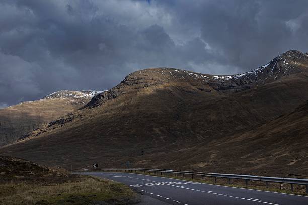 Dramatic scenes at mountain pass with snowcapped mountains and grey clouds at the Scottish Highlands
