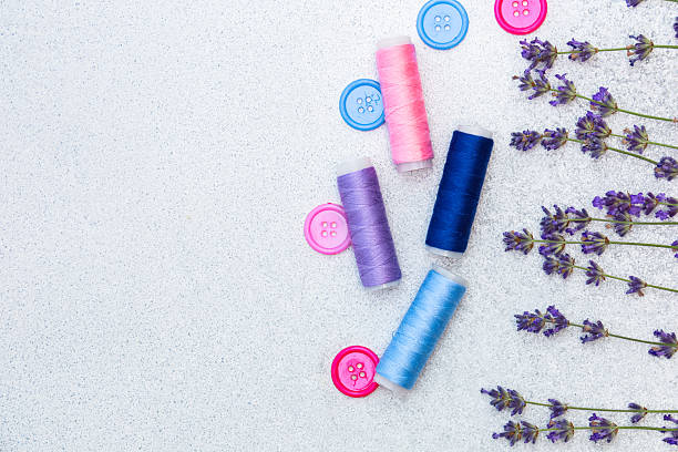 istock Spools of thread in various colors are placed next to lavender flowers on a light surface 2254636579